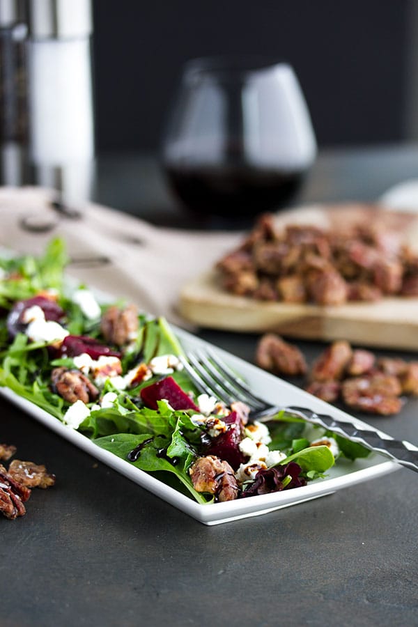 a plate of pickled beet salad with some maple roasted pecans and a glass of wine 