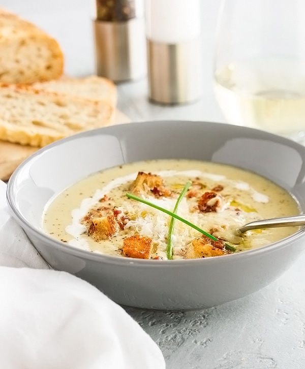 A bowl of creamy broccoli and cauliflower soup with homemade croutons on top