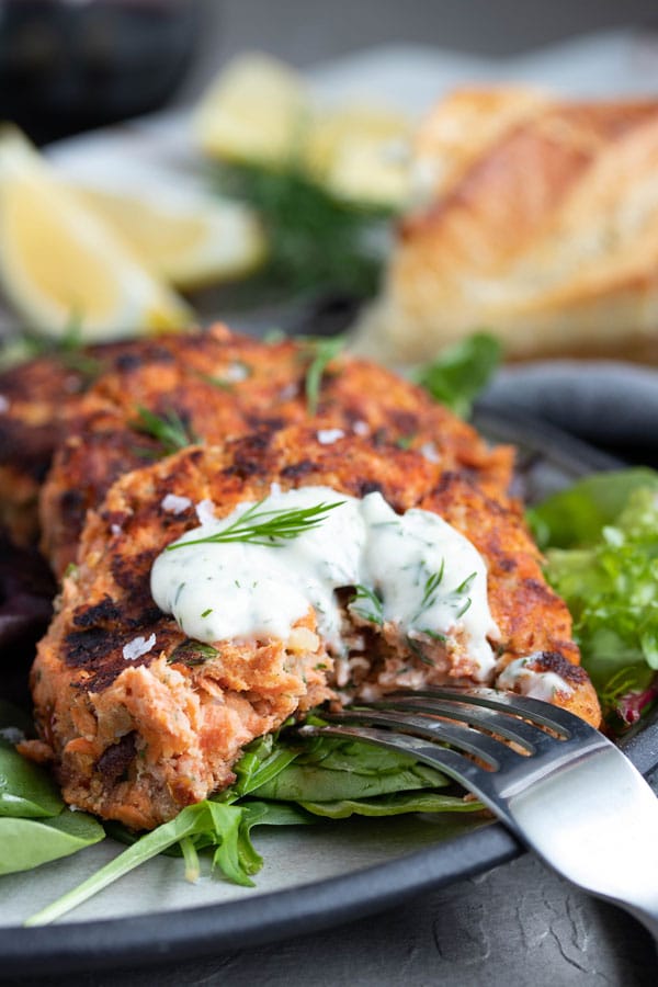 a fork digging into a salmon cake.  it looks tender and delicious. 