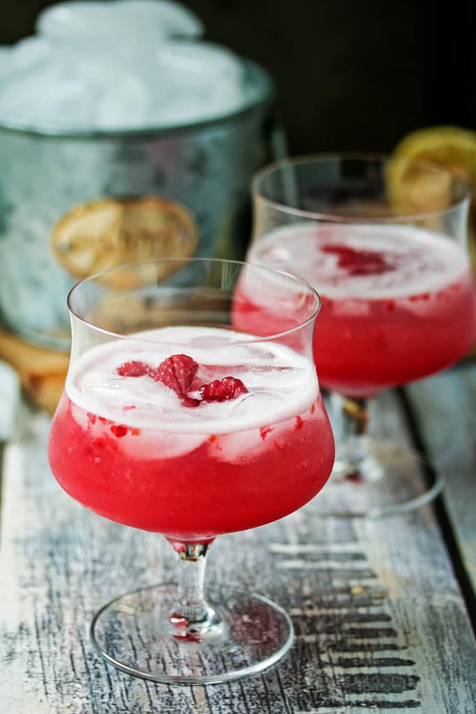 Raspberry & Limoncello Vodka Sour in a glass with raspberries on top
