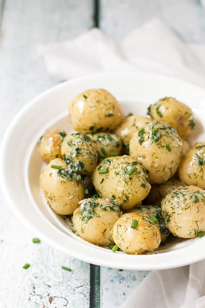 potato side dish with garlic and dill in a white serving bowl