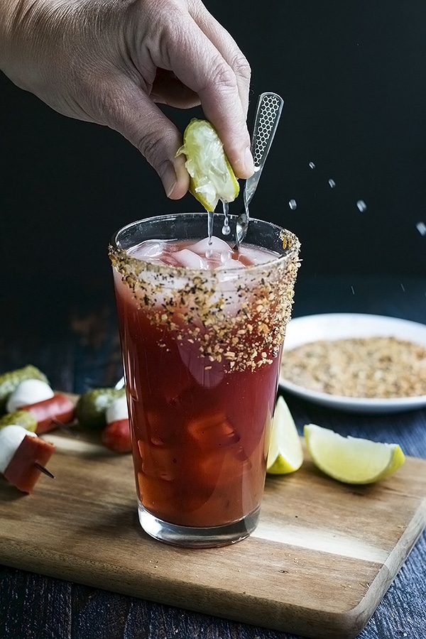 squeezing lime into a caesar cocktail 