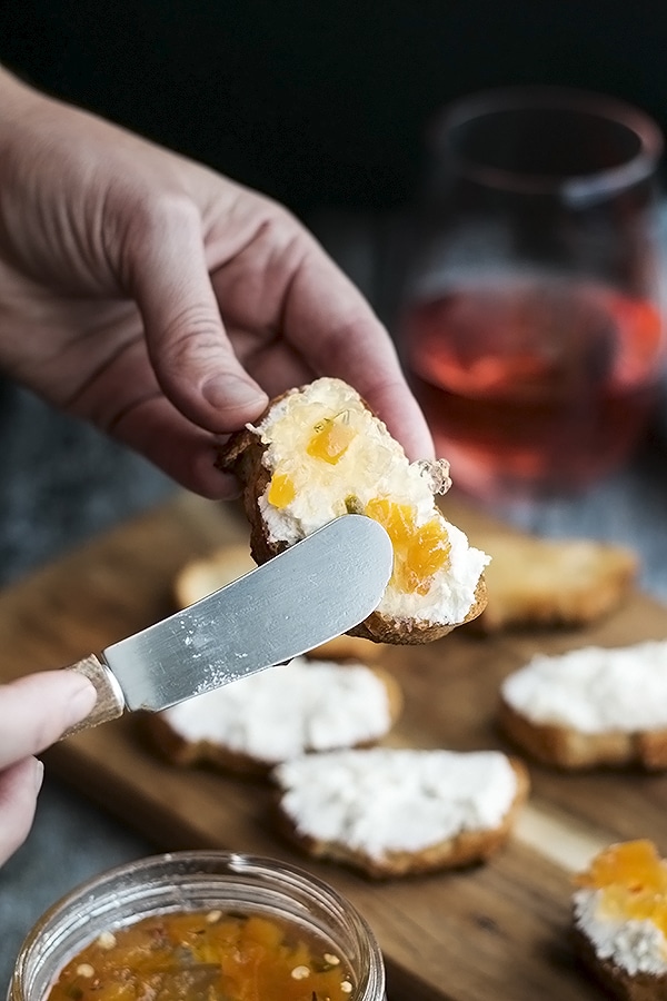a knife spreading wine jelly on a crostini