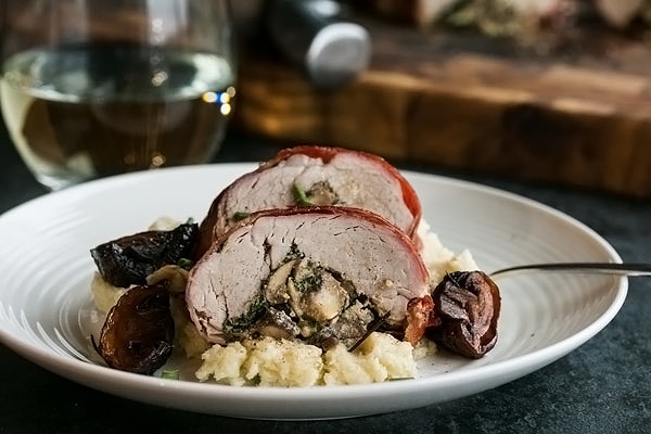 stuffed pork tenderloin served on a plate with mashed potatoes
