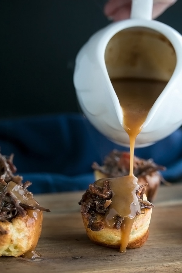 pouring gravy over the stuffed yorkshire puddings