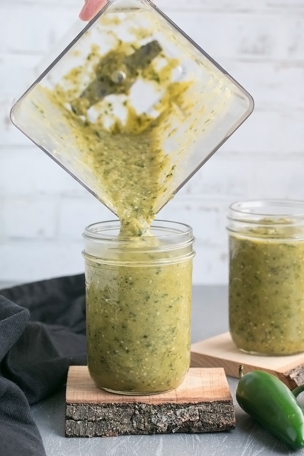 pouring authentic salsa verde out of the blender into a mason jar