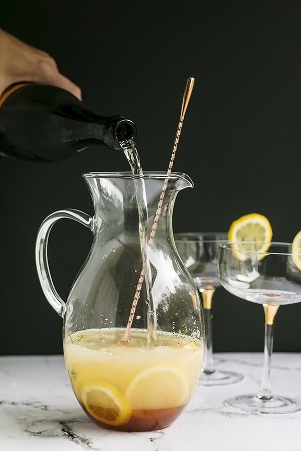 pouring the bubbly into the pitcher for the bees knees cocktail