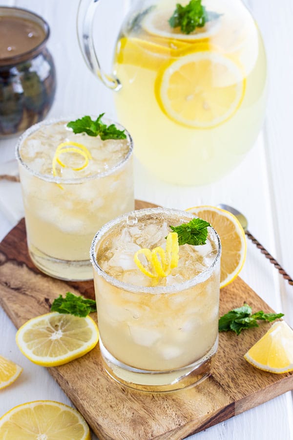 two glasses and a pitcher of whiskey lemonade