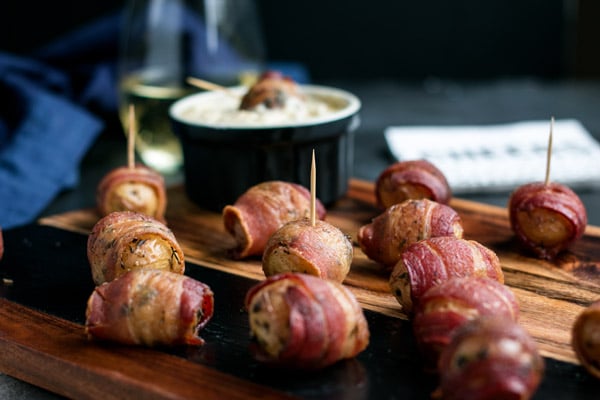 bacon wrapped potatoes with toothpicks to eat them easy. One potato is dipped in the cheese dip in the back