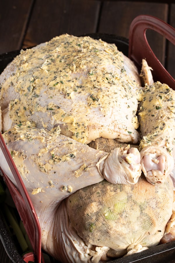 a brined and stuffed turkey in a roaster pan with butter and rosemary rubbed on the skin