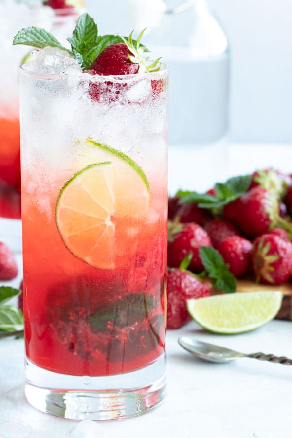 A strawberry mojito with a strawberry and mint on top for garnish