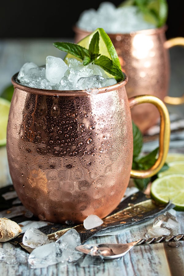 a close up picture of a copper mug with crushed ice, a sprig of mint and a lime