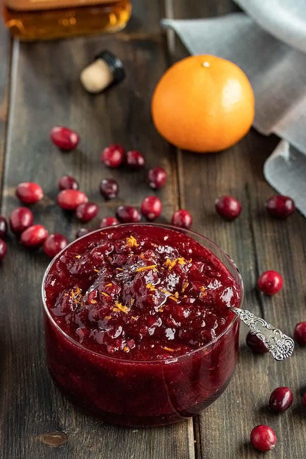 a glass bowl with homemade cranberry sauce inside and orange zest grated on top
