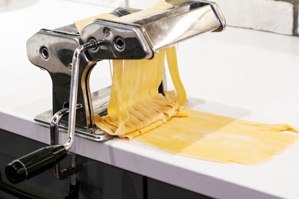 fettuccine noodles being made by the pasta maker