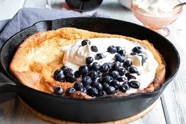 dutch baby in the pan with blueberries and whipped cream