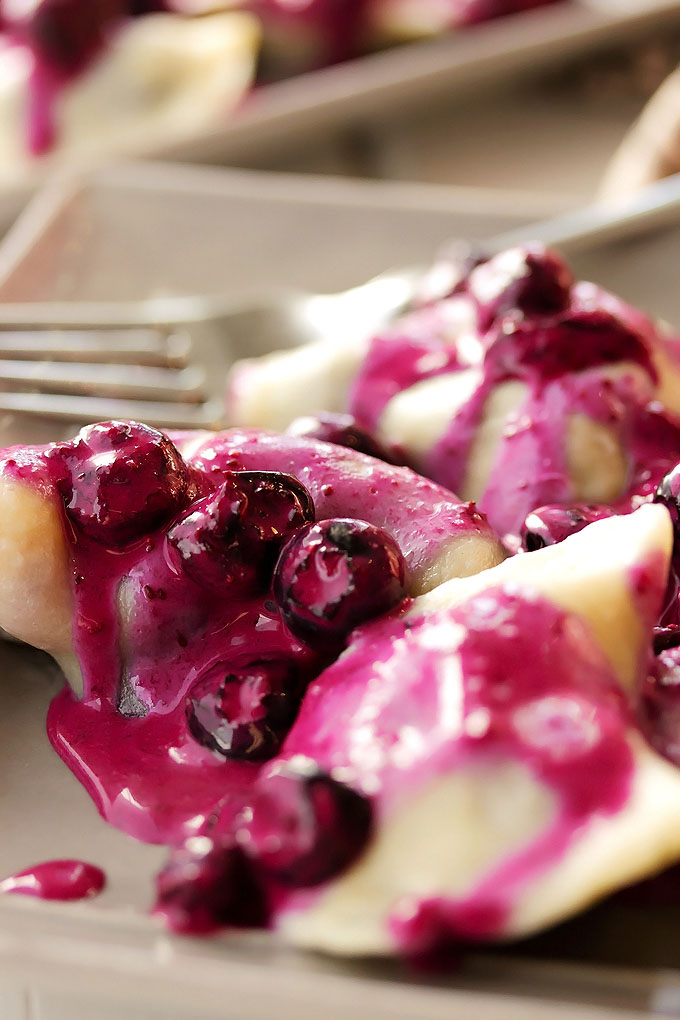 close up of blueberry perogies with blueberry sauce